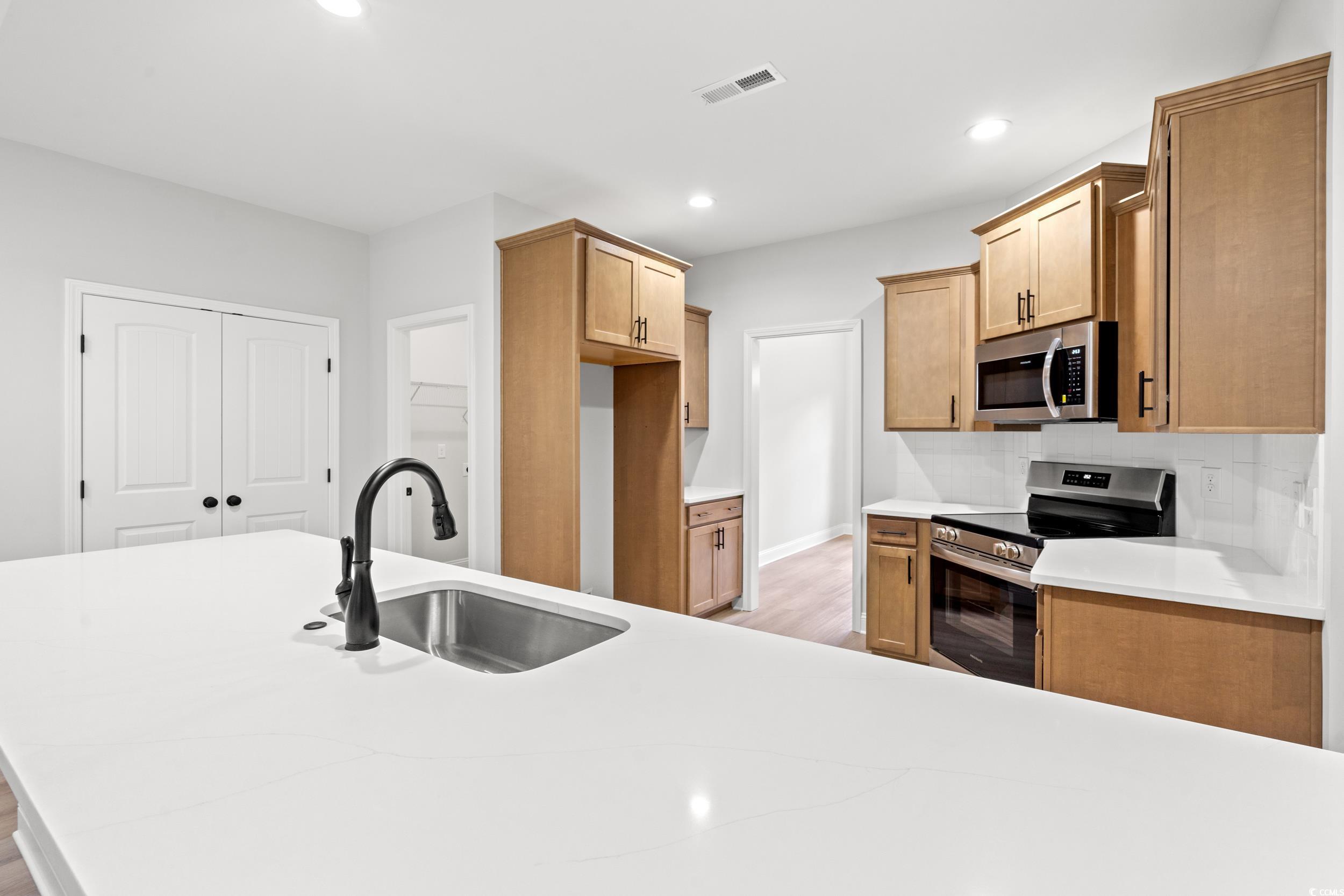 839 Francis Parker Road Georgetown, SC 29440 - Photo 10 of 38 Kitchen featuring appliances with stainless steel finishes, light wood finished floors, recessed lighting, light countertops, and decorative backsplash