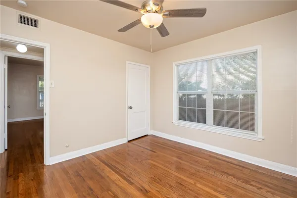 an empty room with wooden floor a ceiling fan and closet