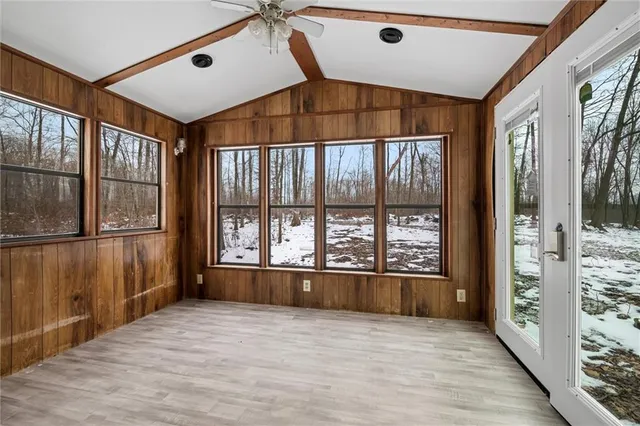 a view of an empty room with a window and hardwood floor