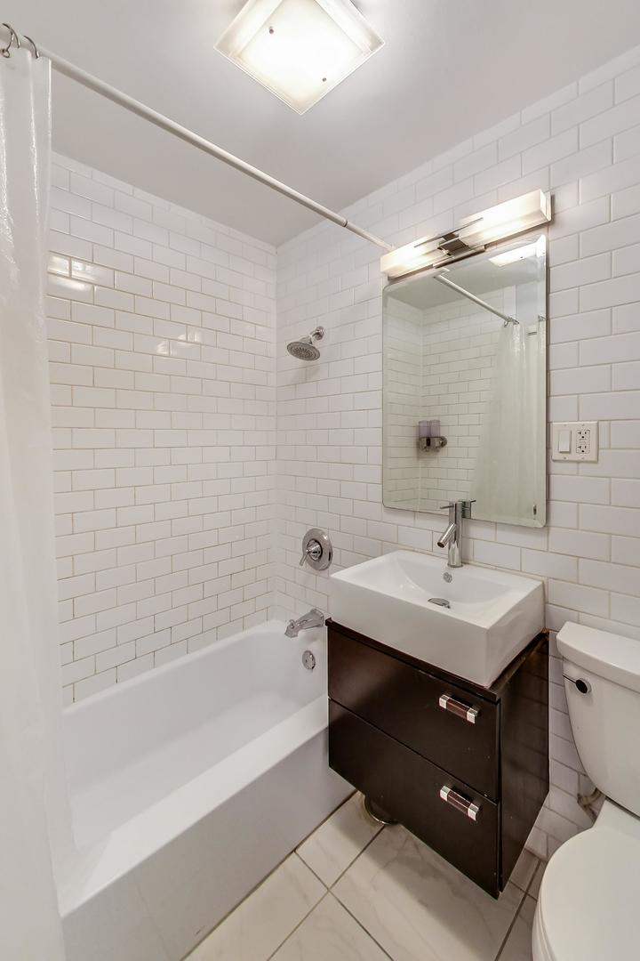 2930 North Sheridan Road, Unit 802 Chicago, IL 60657 - Photo 12 of 30 a bathroom with a sink toilet a mirror and shower