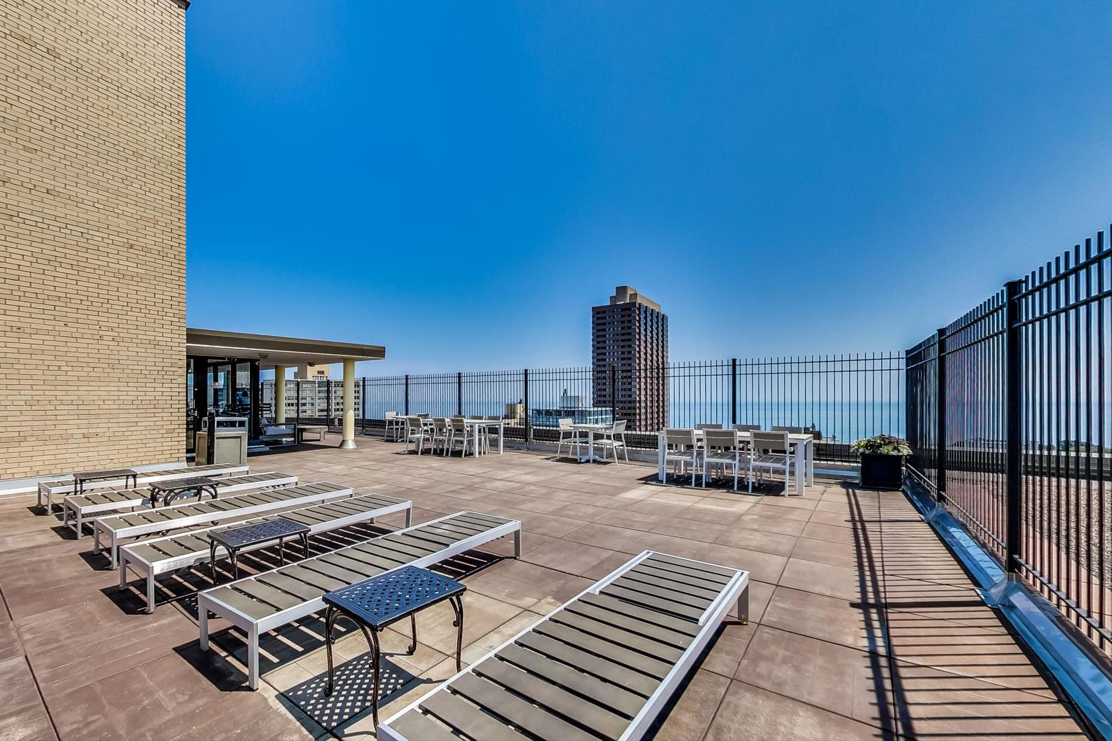 2930 North Sheridan Road, Unit 802 Chicago, IL 60657 - Photo 18 of 30 a roof deck with table and chairs and potted plants
