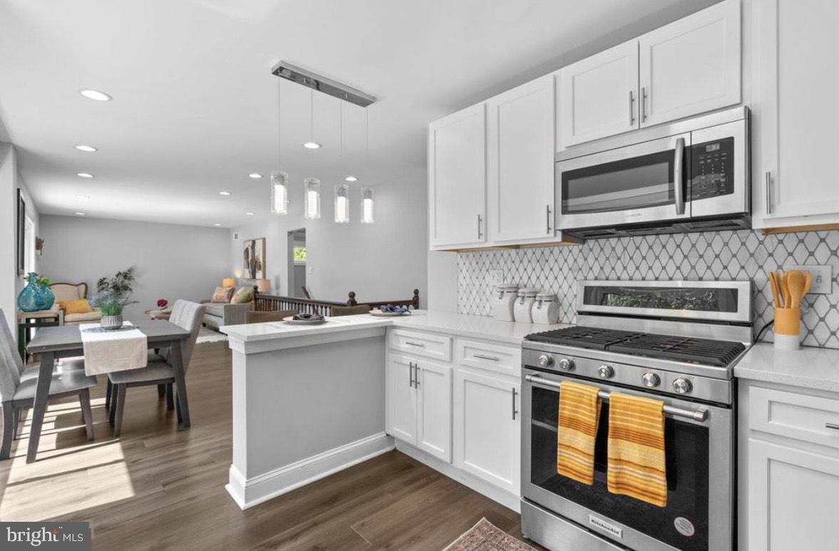 9802 Cherry Tree Lane Silver Spring, MD 20901 - Photo 13 of 33 a kitchen with stainless steel appliances granite countertop a stove top oven a sink dishwasher and white cabinets with wooden floor