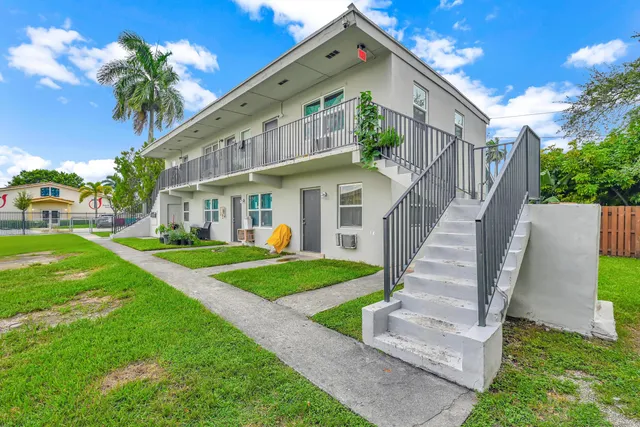 a view of a house with a yard and potted plants