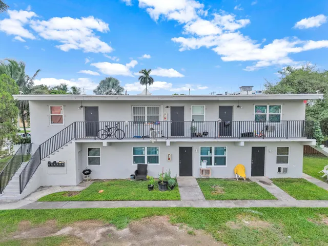 a front view of a house with a yard and potted plants