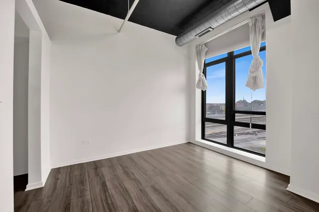 a view of an empty room with wooden floor and windows