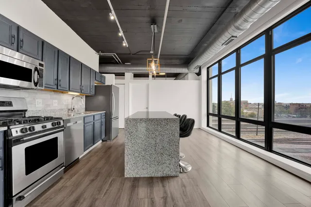 a kitchen with stainless steel appliances granite countertop a stove a refrigerator a sink and a wooden floors