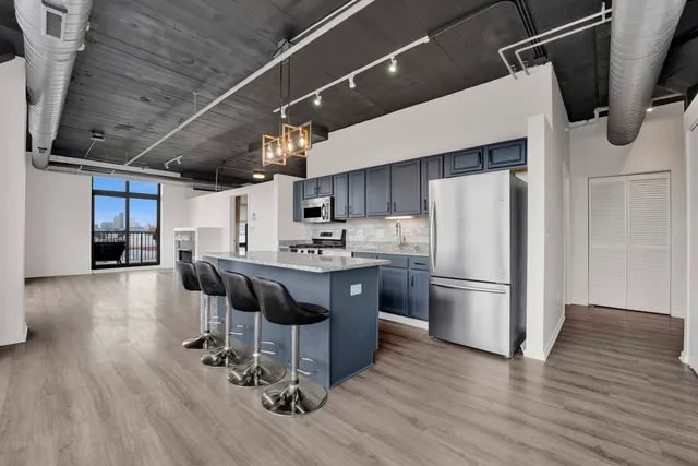 a kitchen with stainless steel appliances a refrigerator a stove a sink dishwasher and a dining table with wooden floor