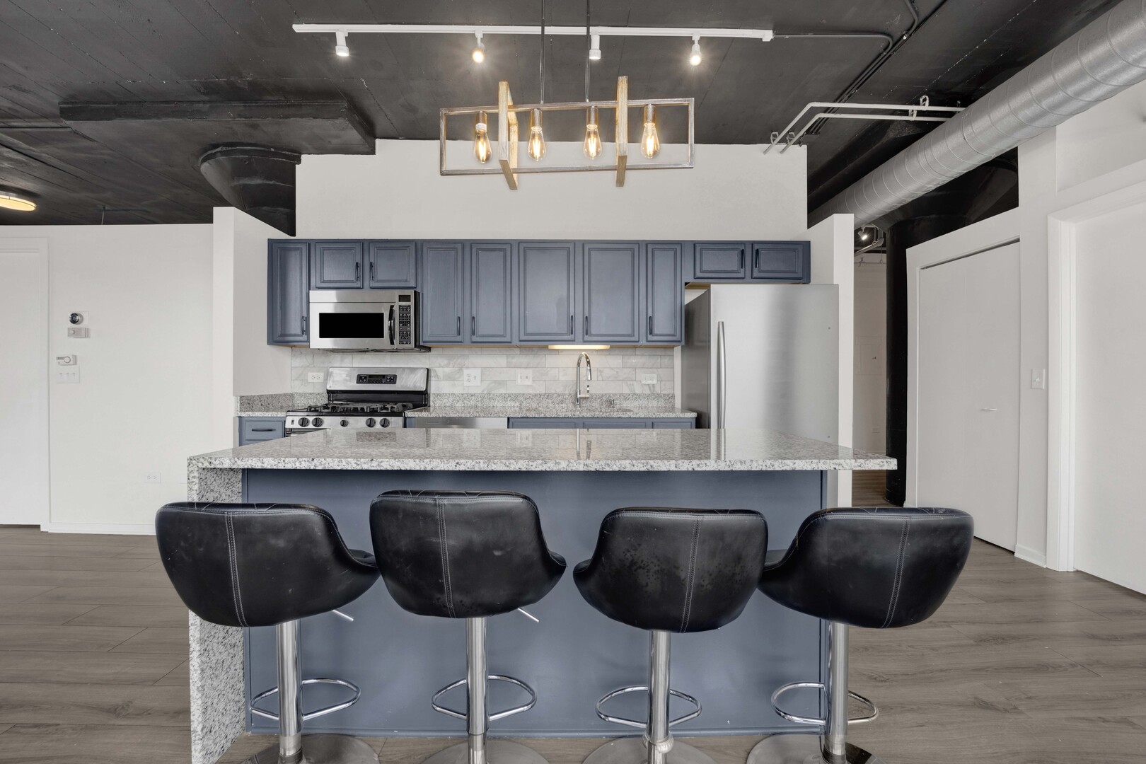 1524 South Sangamon Street, Unit 401 Chicago, IL 60608 - Photo 7 of 55 a kitchen with granite countertop a counter space chairs stainless steel appliances and cabinets