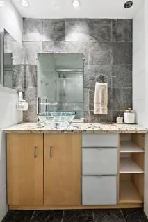 a bathroom with a granite countertop sink a mirror and shower