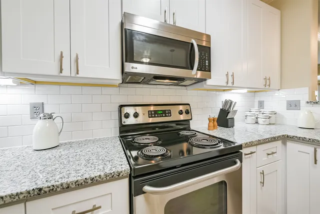 a kitchen with granite countertop a stove top oven microwave and cabinets