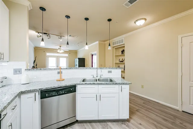 a kitchen with a sink dishwasher and white cabinets with wooden floor