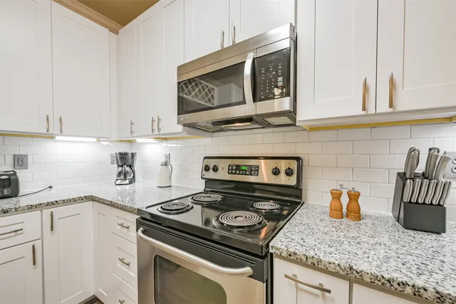 a kitchen with granite countertop stainless steel appliances and white cabinets