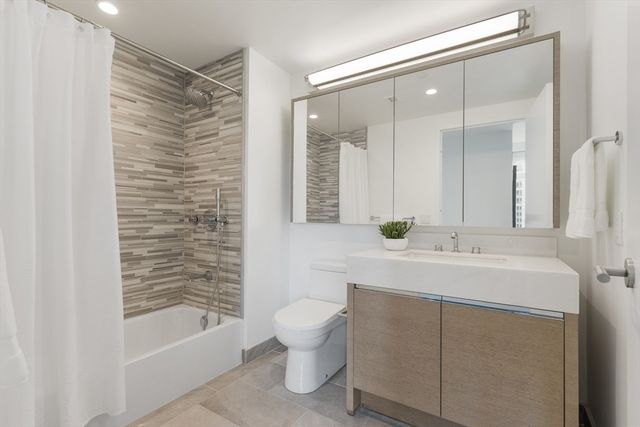 a bathroom with a bathtub shower sink mirror and toilet