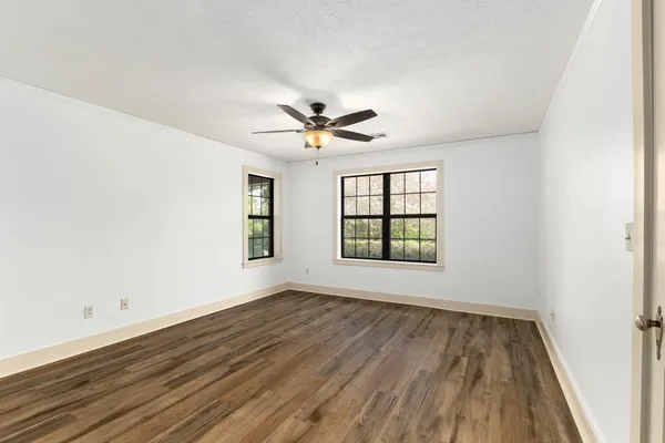 an empty room with wooden floor and windows