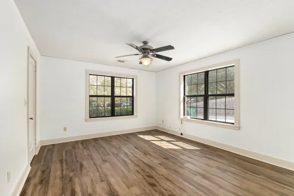 an empty room with wooden floor and windows