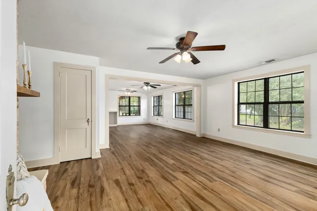 a view of empty room with wooden floor and fan