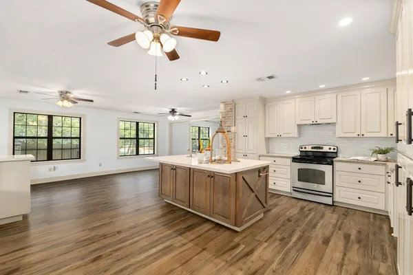 a large kitchen with stainless steel appliances granite countertop a stove and a wooden floors