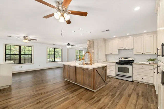 a large kitchen with stainless steel appliances granite countertop a stove and a wooden floors