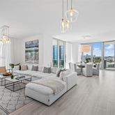 a living room with furniture kitchen view and a large window
