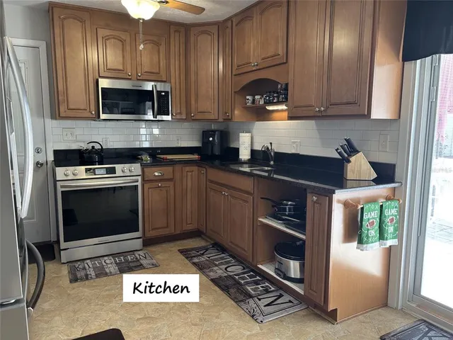 a kitchen with granite countertop a stove a microwave a sink and cabinets