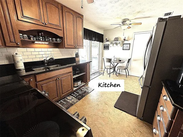 a kitchen with stainless steel appliances granite countertop a refrigerator a stove and a sink