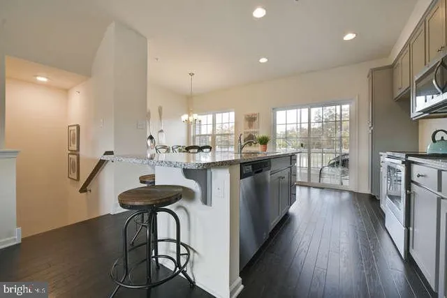 a kitchen with stainless steel appliances kitchen island hardwood floor sink stove and wooden cabinets