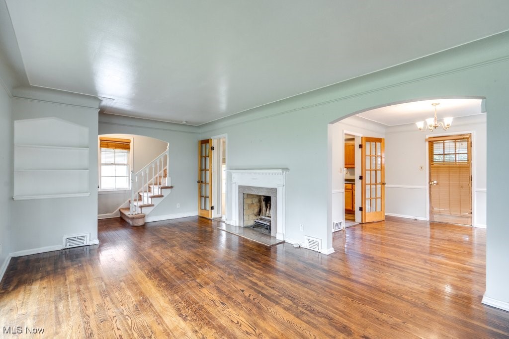 13677 Cedar Road Cleveland, OH 44118 - Photo 12 of 50 Unfurnished living room with arched walkways, wood finished floors, stairway, a premium fireplace, and crown molding