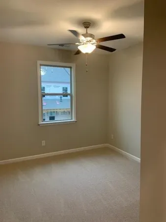an empty room with a chandelier fan and windows