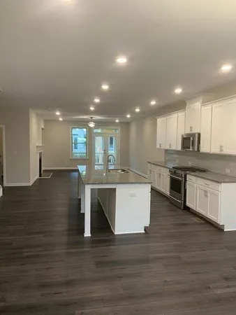 a open kitchen with kitchen island a sink dishwasher a stove and a refrigerator with wooden floor