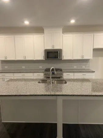 a kitchen with granite countertop white cabinets and a sink