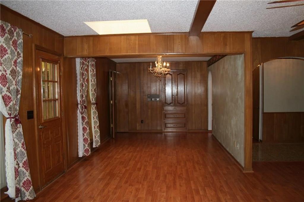 2107 Forest Grove Estates Road Allen, TX 75002 - Photo 8 of 13 Hallway featuring wood walls, wood finished floors, a chandelier, arched walkways, and a textured ceiling