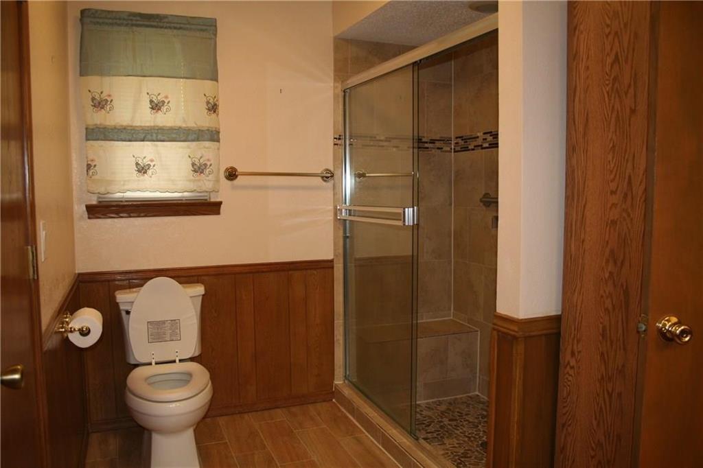 2107 Forest Grove Estates Road Allen, TX 75002 - Photo 10 of 13 Bathroom with wainscoting, a stall shower, wooden walls, and wood finish floors