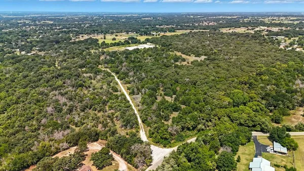 an aerial view of residential houses with outdoor space and trees