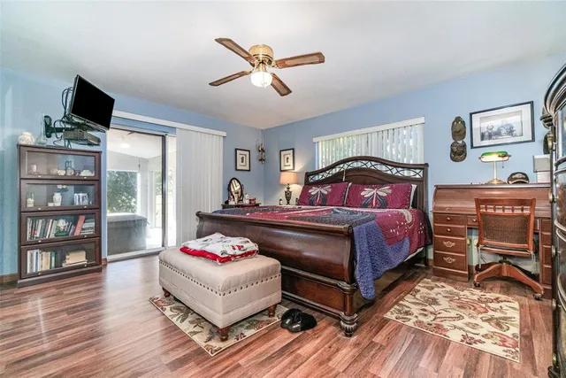 a bedroom with a bed and dresser with wooden floor