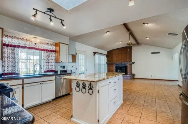 a kitchen with stainless steel appliances kitchen island granite countertop a table chairs and a refrigerator