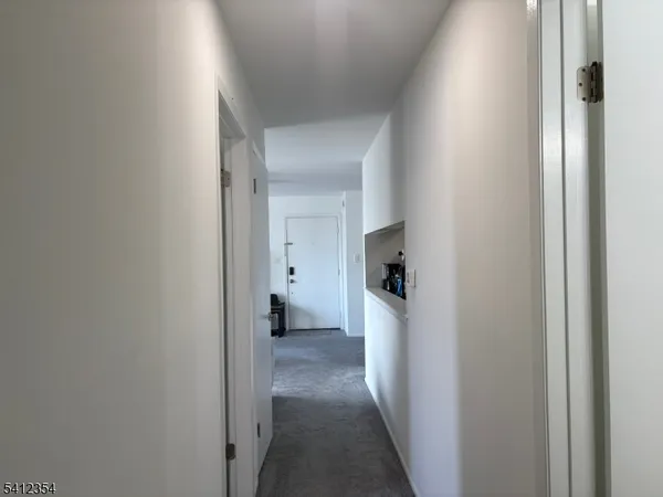 a view of a hallway with a white cabinet and a refrigerator