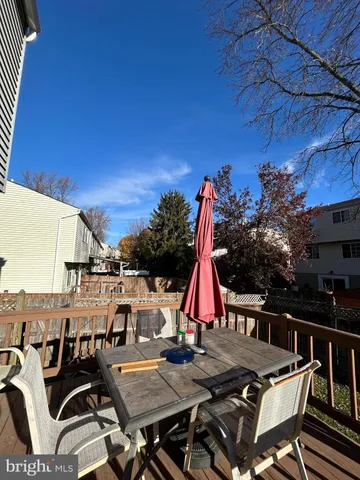a view of a roof deck with table and chairs a barbeque with wooden floor and fence