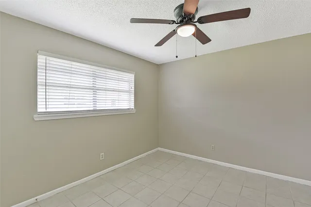 an empty room with a window and a fan