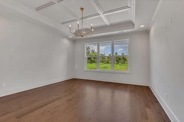 an empty room with wooden floor chandelier and windows