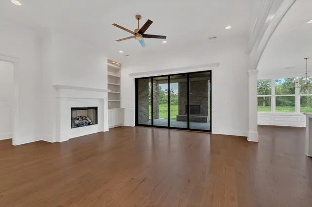 an empty room with wooden floor fireplace and windows