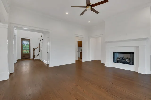 a view of an empty room with wooden floor and a fireplace