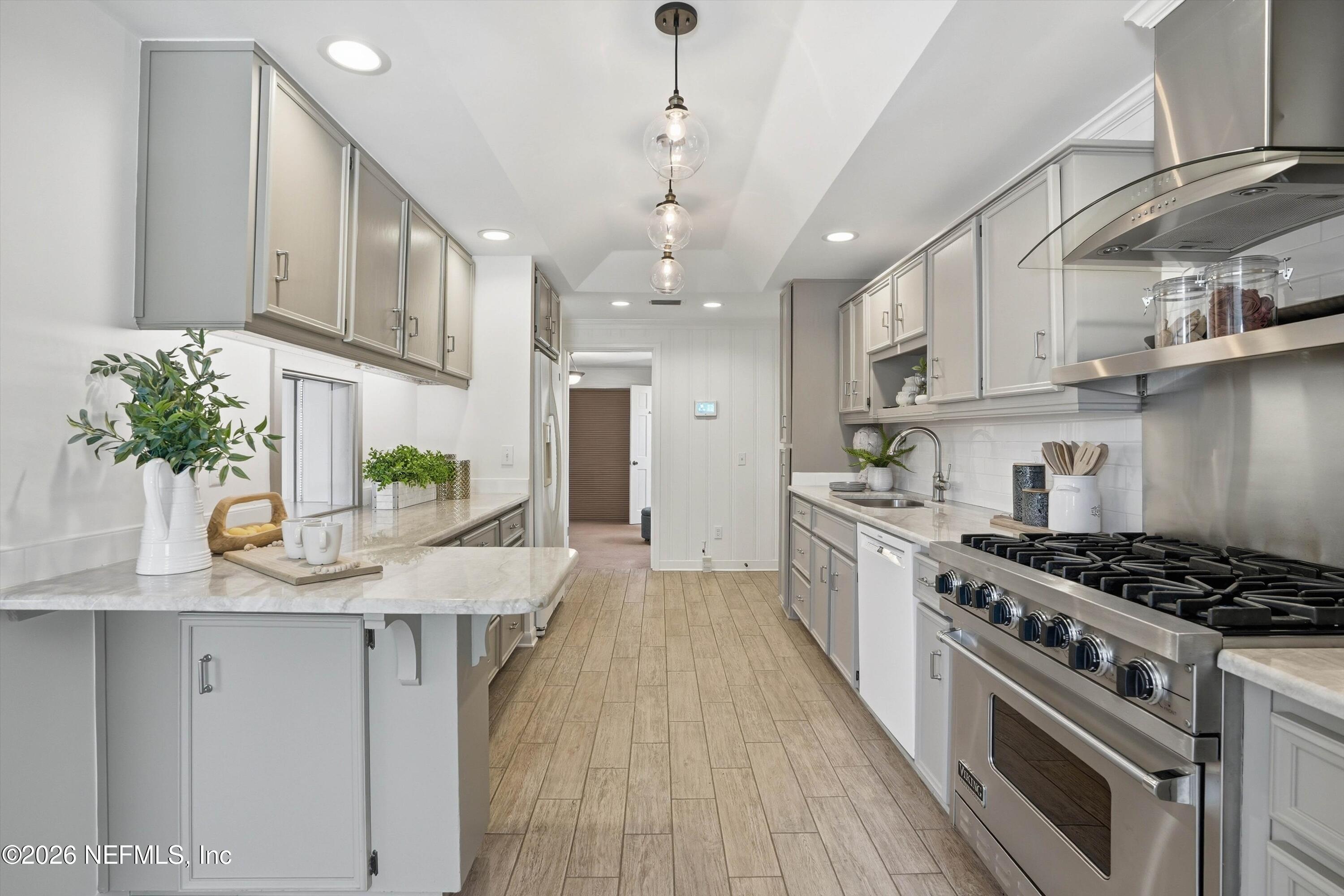 833 Sorrento Road Jacksonville, FL 32207 - Photo 14 of 68 a kitchen with stainless steel appliances kitchen island granite countertop a stove a sink dishwasher and white cabinets with wooden floor