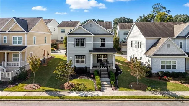 a view of a white house next to a yard with plants and trees
