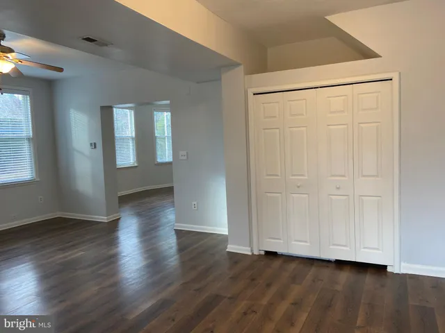 an empty room with wooden floor fireplace and windows