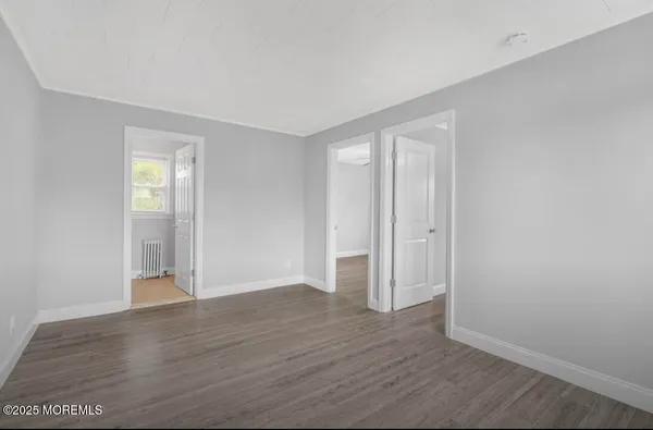 a view of an empty room with wooden floor and closet