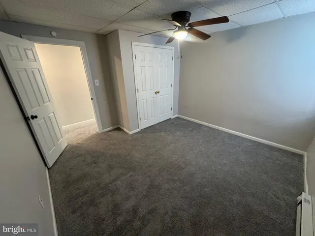 an empty room with windows and fan