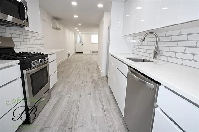 a kitchen with stainless steel appliances granite countertop a sink a stove and a wooden floors