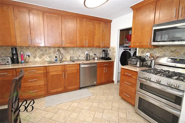 a kitchen with stainless steel appliances a sink a stove a microwave cabinets and a counter top space