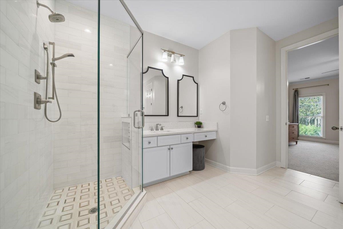 1876 Liles Lane Collierville, TN 38017 - Photo 14 of 36 Spacious bathroom featuring a glass-enclosed shower with custom tile work, a dual vanity with white cabinetry and light-colored countertops, and decorative mirrors