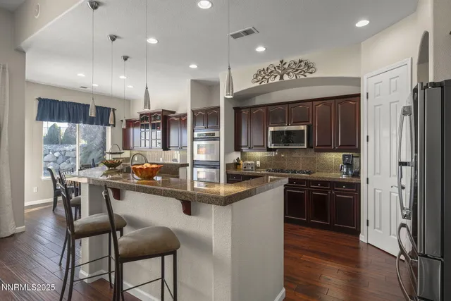 a kitchen with stainless steel appliances granite countertop a refrigerator a stove top oven a sink dishwasher and white cabinets with wooden floor